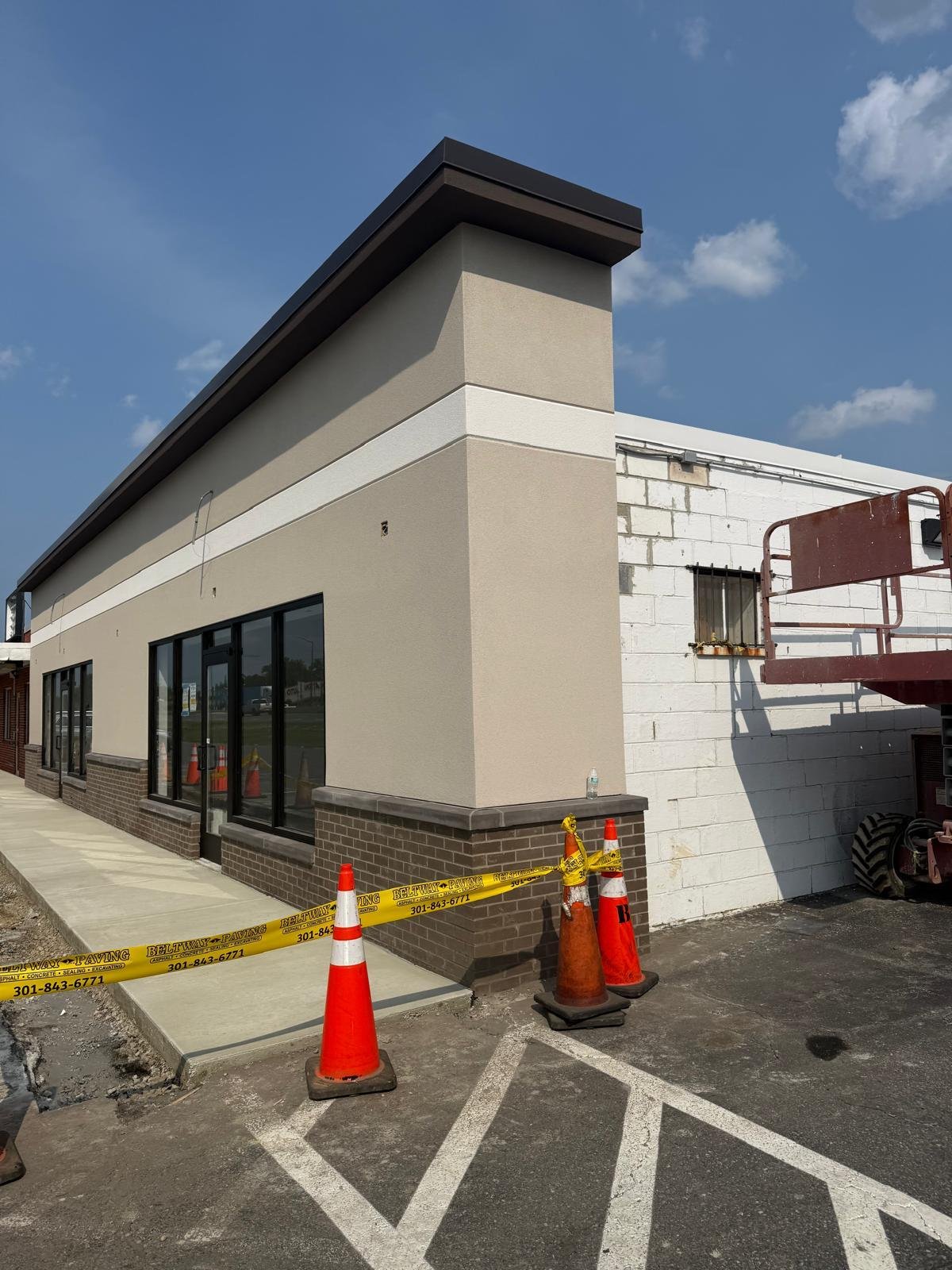 Commercial building exterior renovation with completed facade, storefront windows and site work in progress